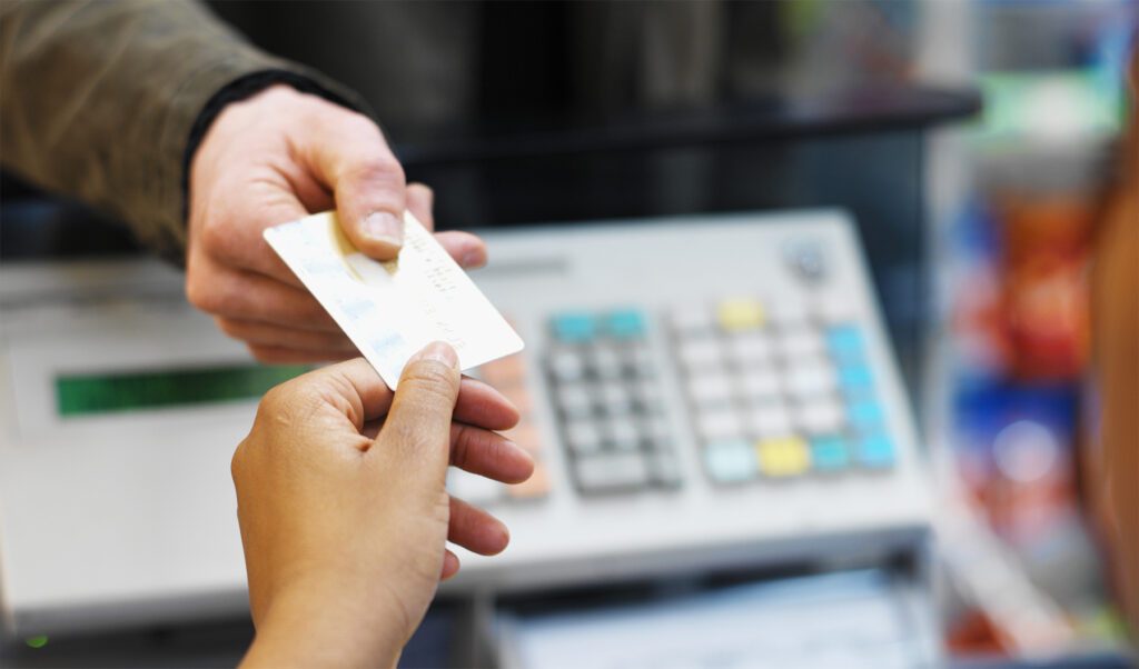 Patient handing credit card to clinic receptionist for payment at front desk.