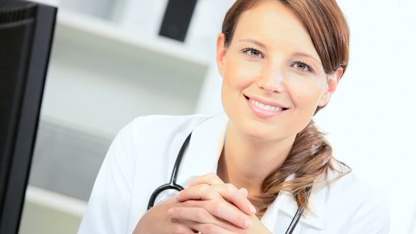Smiling female doctor sitting at desk in medical office with stethoscope.