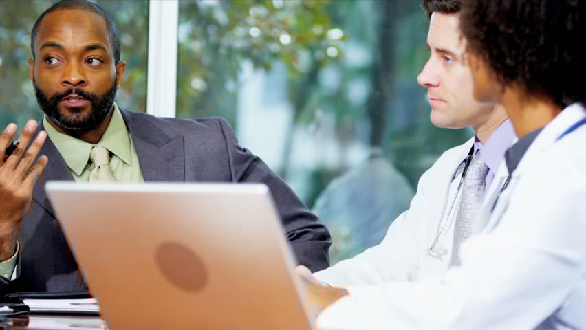 Medical professionals and business consultants reviewing medical data in conference room.