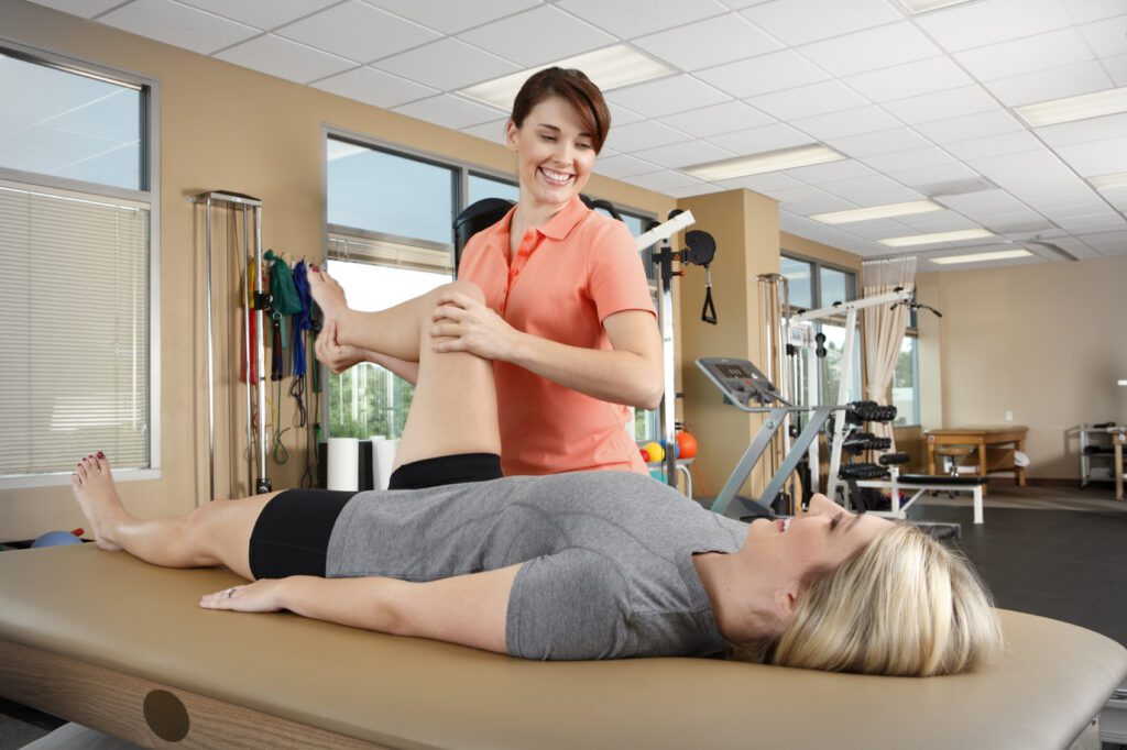 Physical therapist performing leg mobility exercise with patient during rehabilitation session.