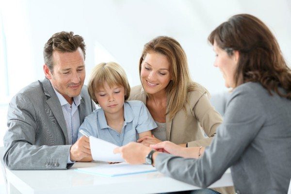 Family meeting with a professional woman reviewing documents at a desk.