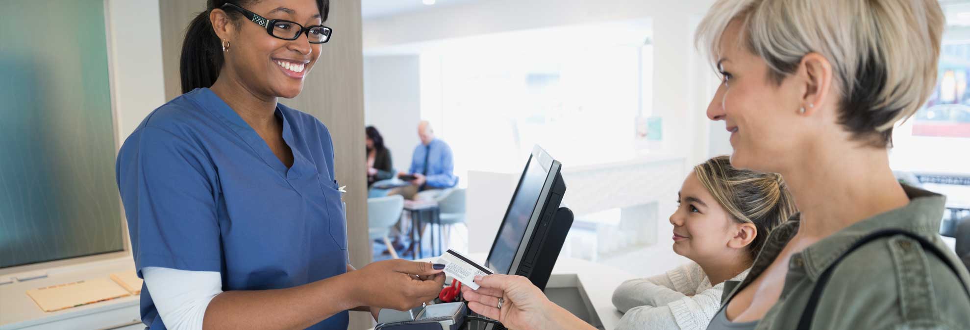 Healthcare staff member assisting patient with billing and payments at reception.