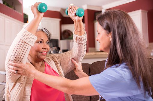 Senior woman performing rehabilitation exercises guided by healthcare professional.