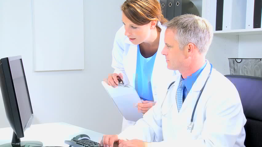 Two medical professionals reviewing patient information on a computer in a bright office.