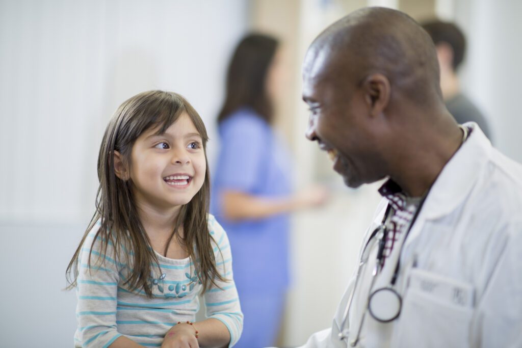 Smiling doctor talking with a happy young girl during a medical appointment.