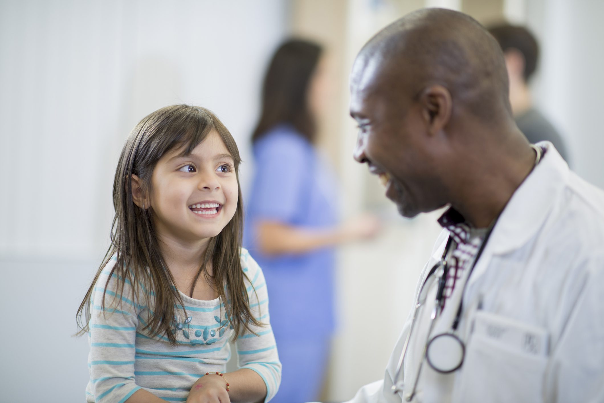 Smiling doctor talking with a happy young girl during a medical appointment.