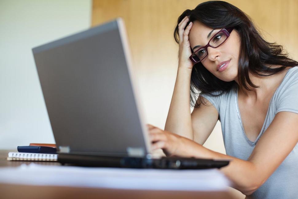 Concerned woman looking at laptop while managing EMR data backup.