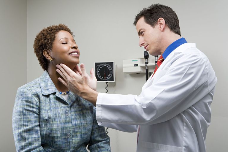 Doctor examining a woman’s neck during a medical appointment in a clinic.