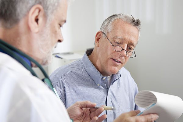 Healthcare professional reviewing patient information with elderly man in a clinic setting.