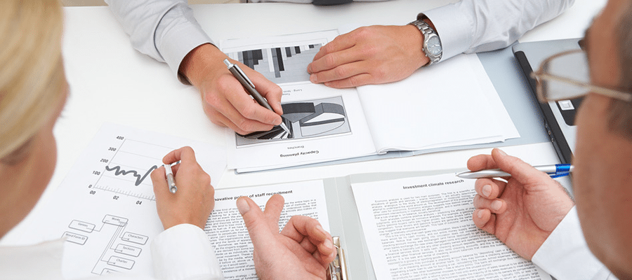 Business professionals reviewing charts and documents with financial graphs and reports on a desk.