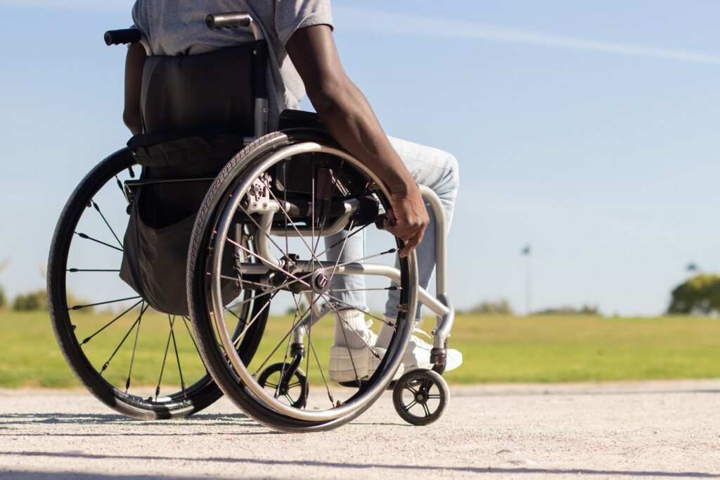 Person in wheelchair outdoors on sunny day, promoting mobility and accessibility.