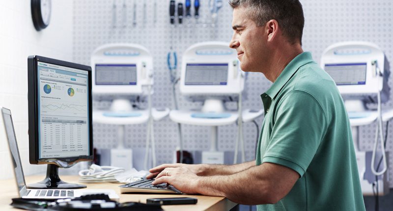Healthcare professional reviewing patient data and reports on computer in medical office.