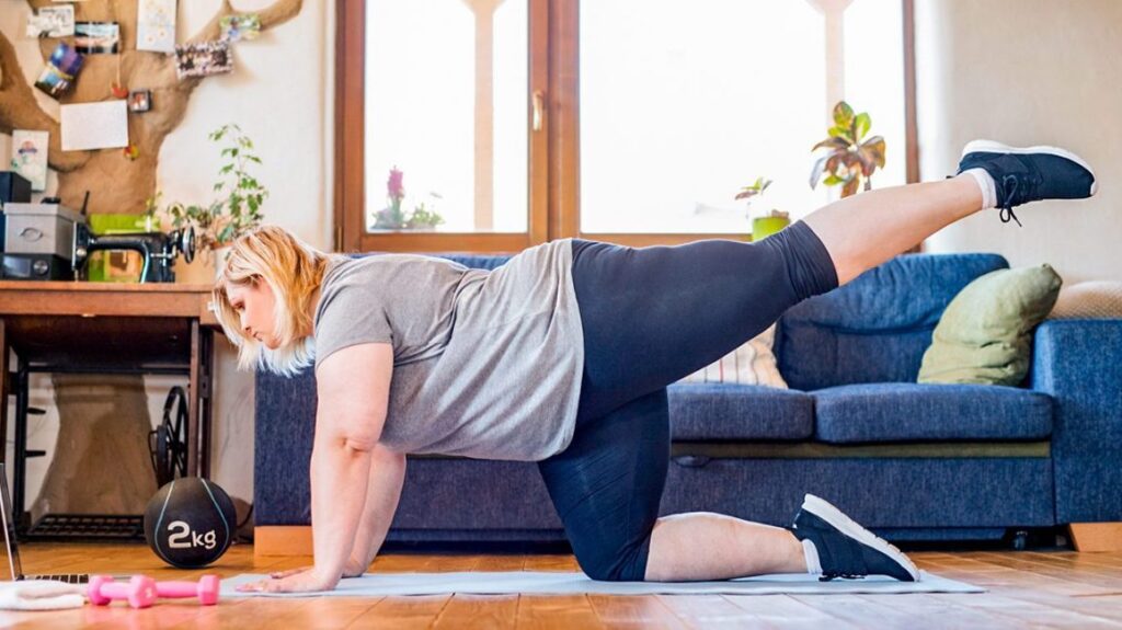 Woman performing home physical therapy exercises with weights and resistance training.