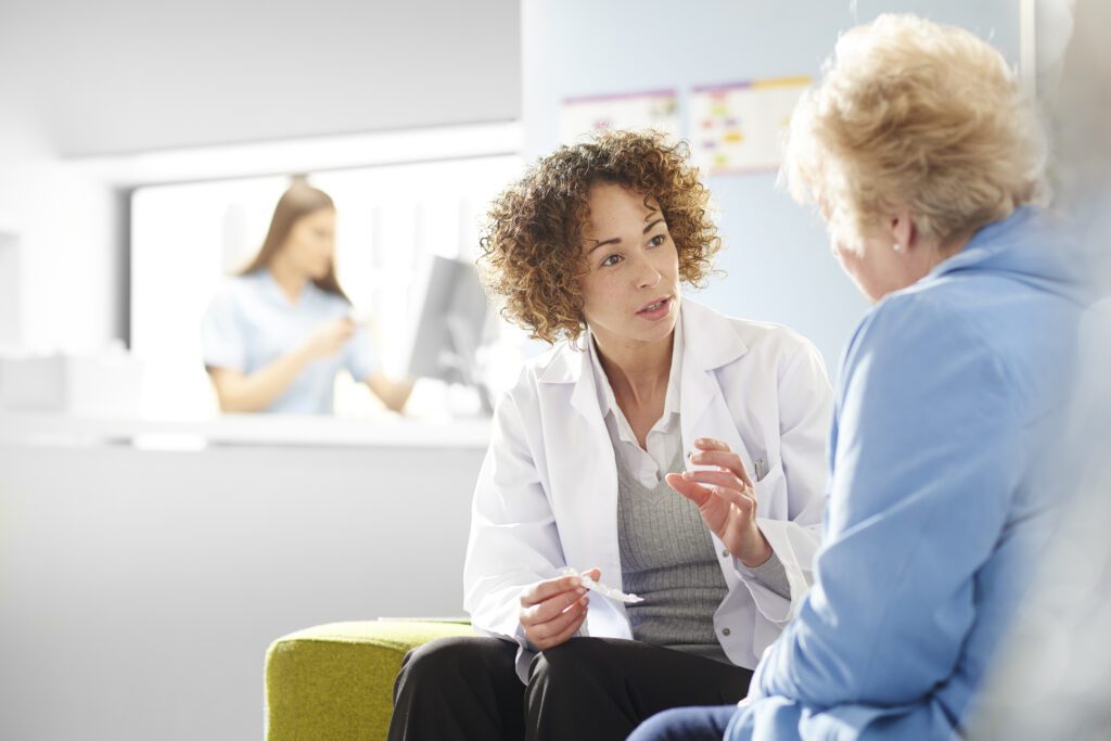 Female doctor discussing treatment plan with elderly patient in a medical clinic.