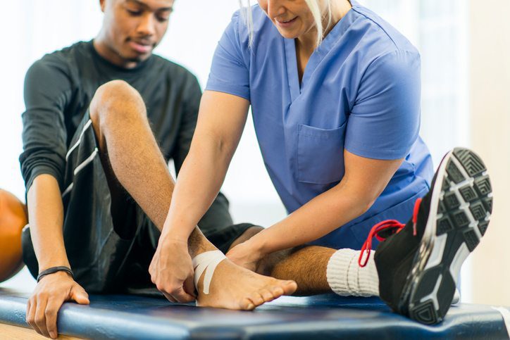 Therapist assisting patient with ankle care as part of doctor-referred therapy.