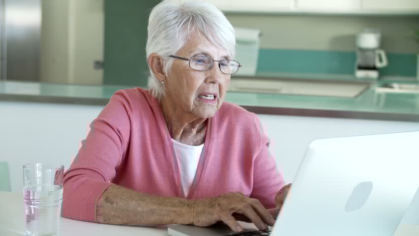 Senior woman using a laptop to book a medical appointment online.