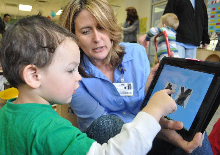 Therapist using tablet app with child during interactive therapy session.