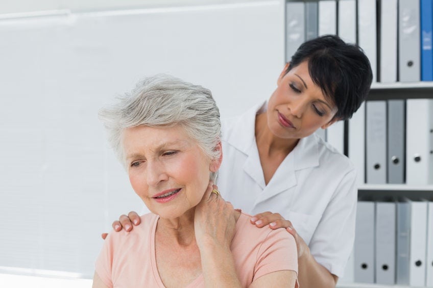 Healthcare professional assessing a senior patient experiencing neck discomfort.