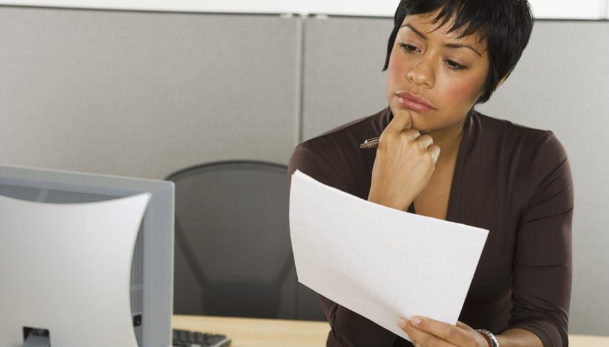 Professional reviewing a press release at her desk in front of a computer.