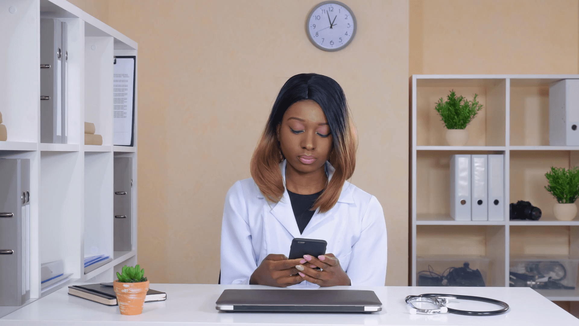 Doctor using smartphone for patient communication in medical office.