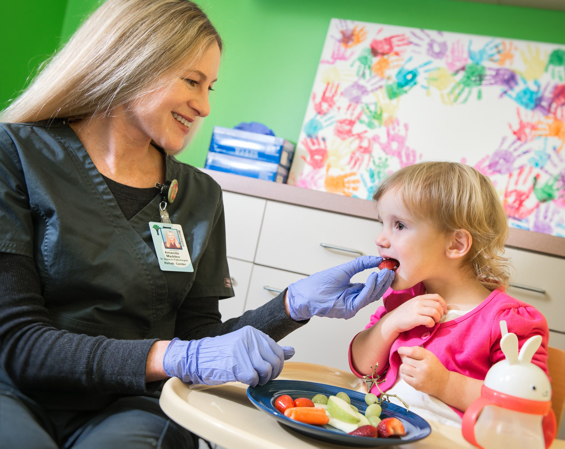 Pediatric therapist helping young child with feeding therapy using healthy foods.