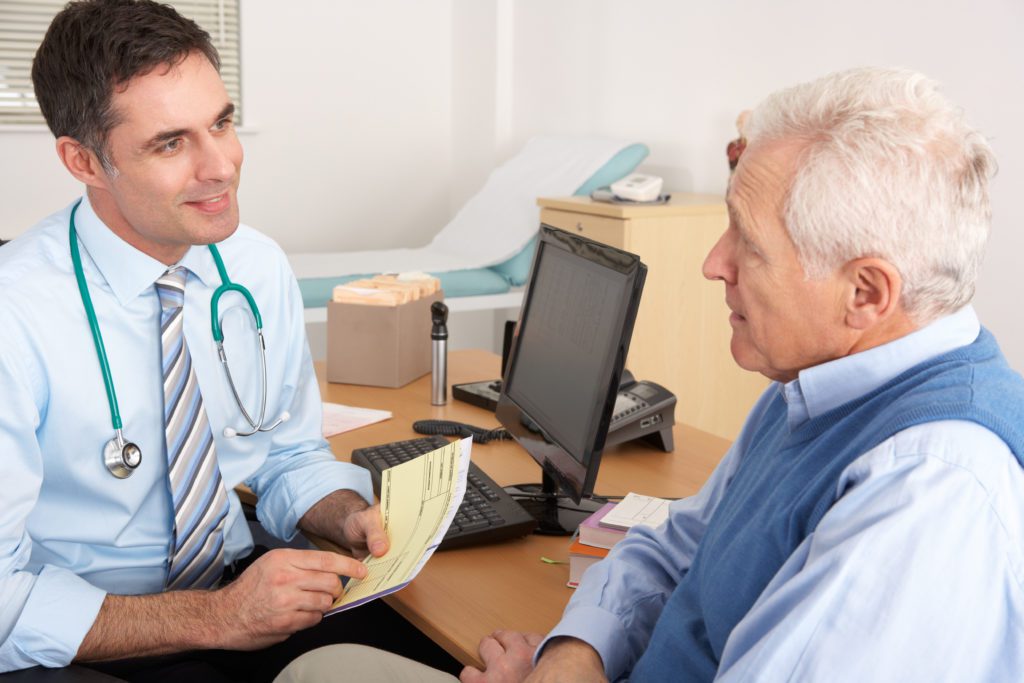 Doctor discussing medical results with senior male patient in clinic office.