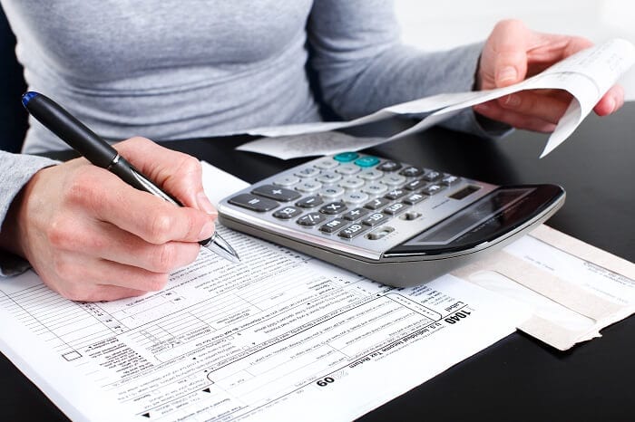Person calculating expenses with receipts and forms, representing EMR reporting and financial management software.