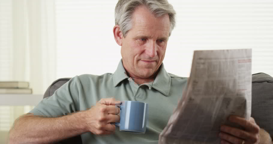 Man reading a newspaper while holding a coffee mug, representing the Practice Perfect Press newsletter.