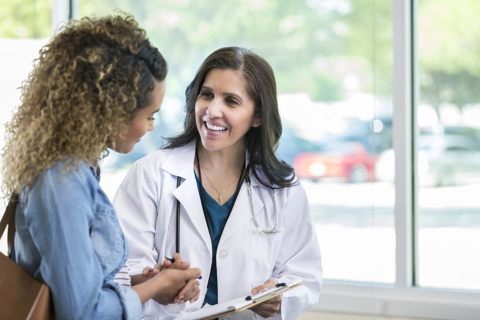 Female clinician holding files speaking to female patient