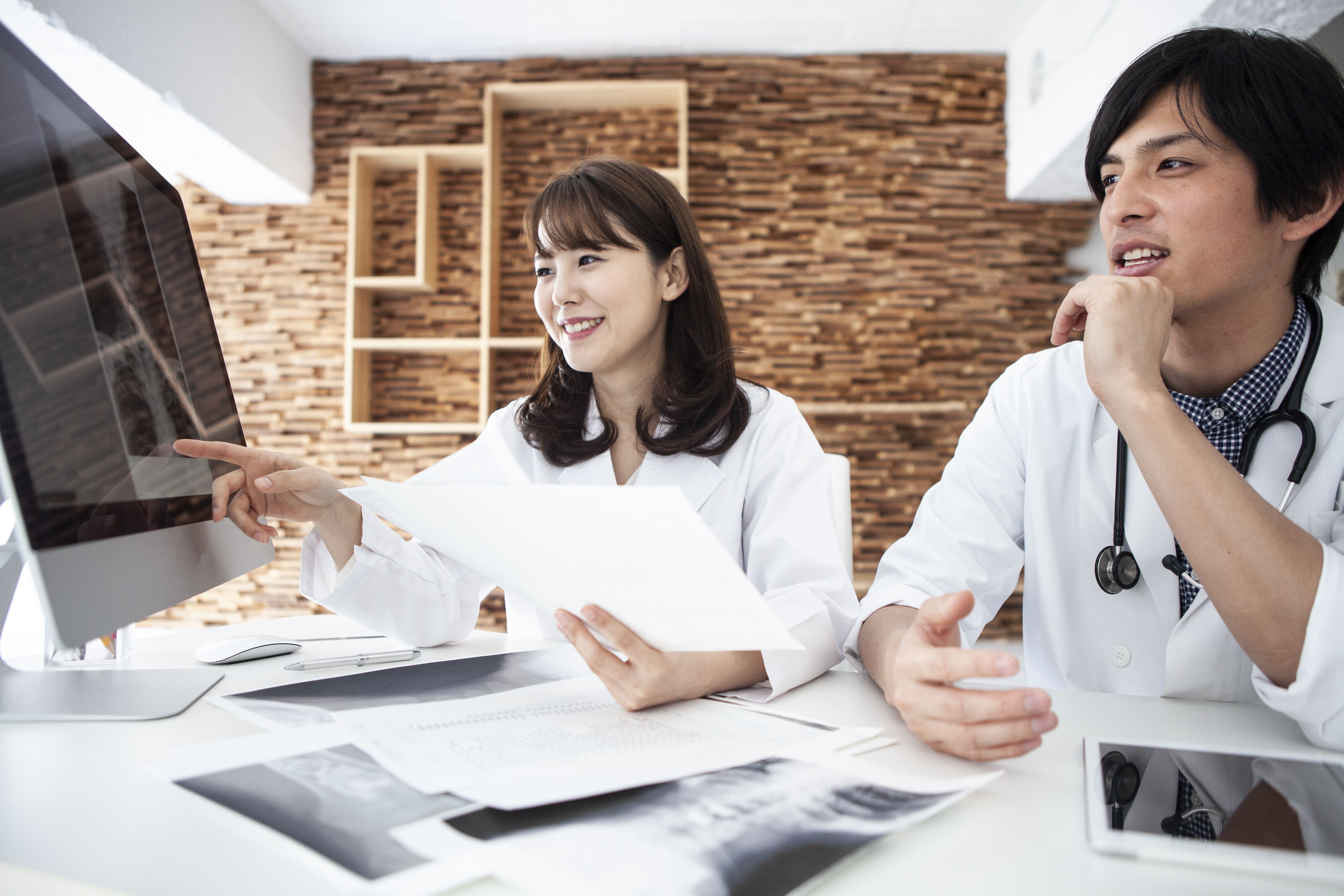 Two physicians sitting in an office looking at medical records on a computer