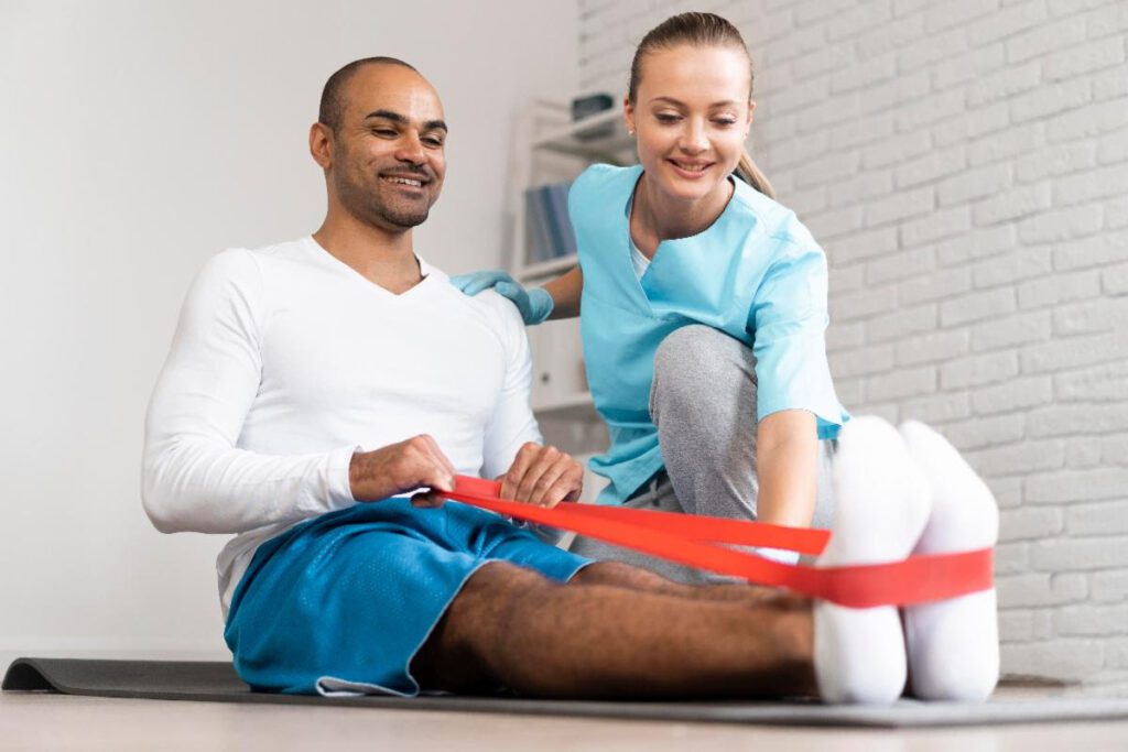 Physiotherapist helping a male patient with resistance band exercises during rehabilitation.