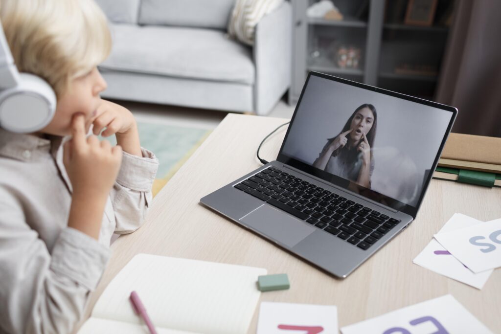Young boy participating in an online speech therapy session with a therapist via video call.