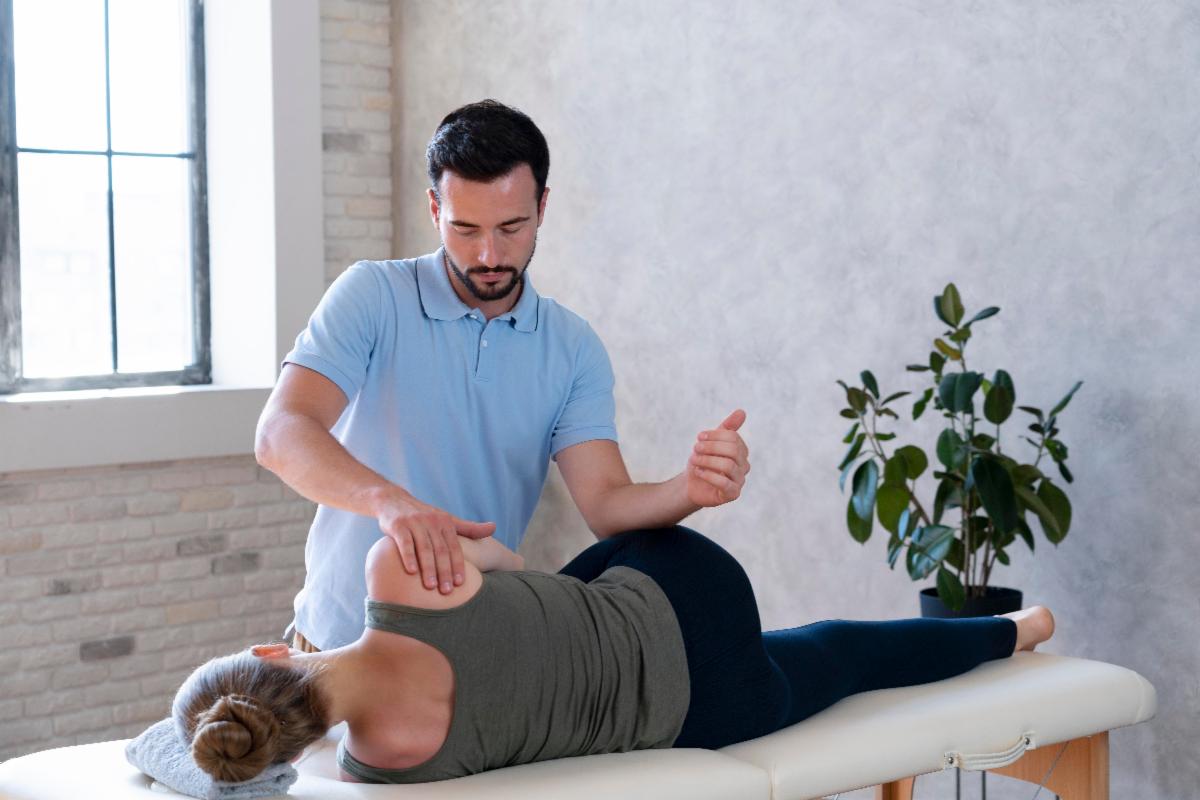 Physiotherapist performing shoulder mobility exercise on female patient during treatment session.