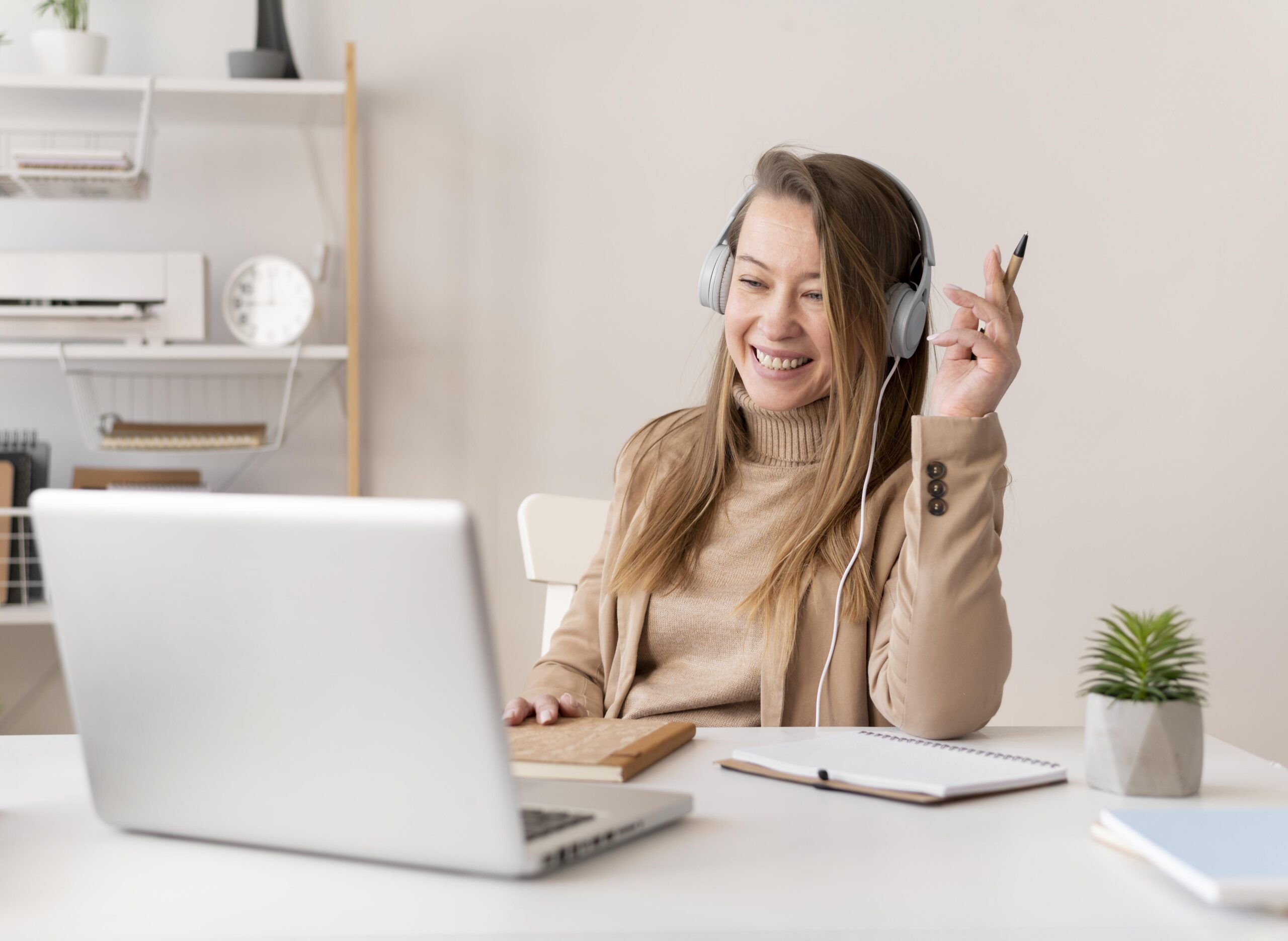 Smiling woman wearing headphones attending a virtual telehealth session on her laptop.