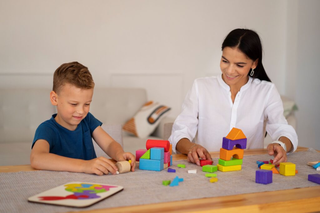 Speech therapist working with a young boy using colourful blocks during a therapy session.