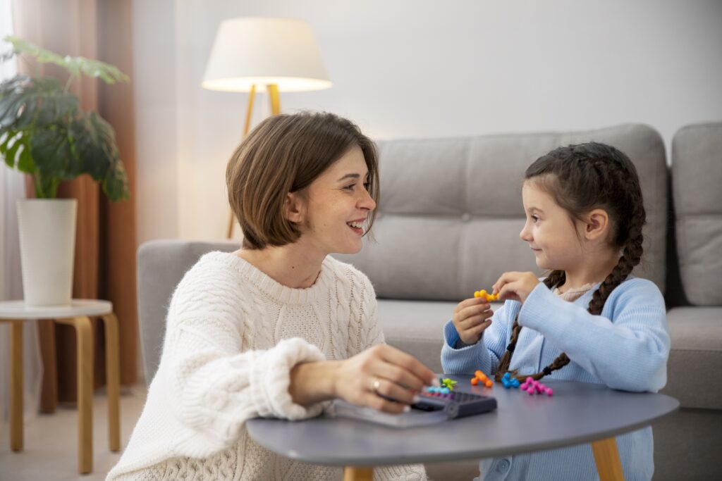 Woman and young girl engaging in a learning activity with bright plastic toys on a small table.